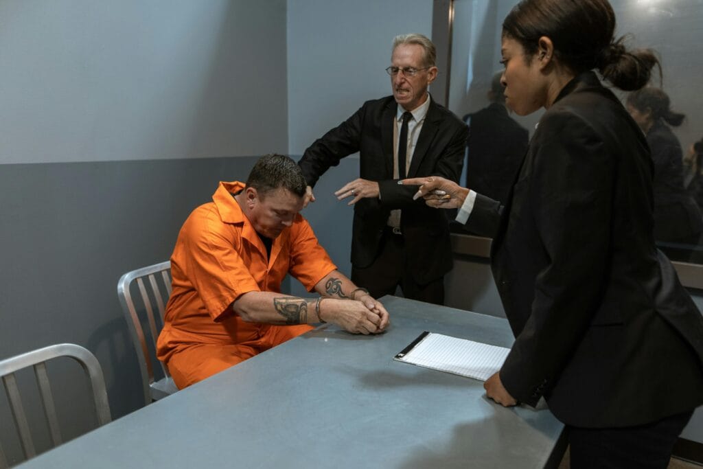 Man in Orange Dress Shirt Sitting Beside Man in Black Suit