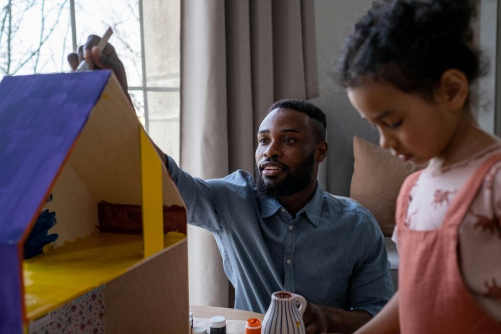A father and daughter enjoying creative time painting together indoors.