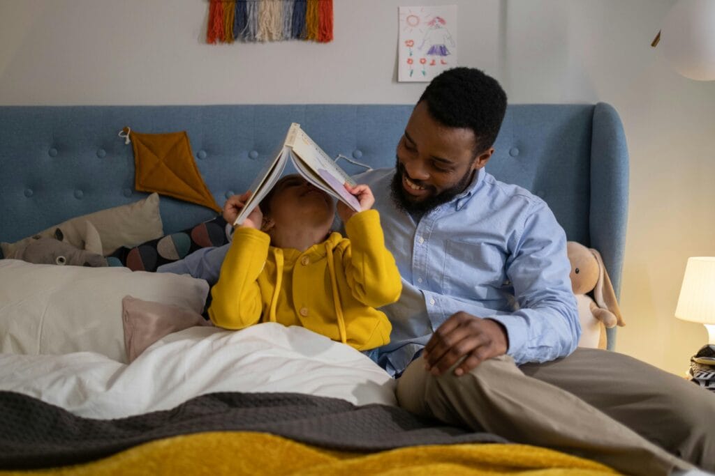 A joyful father reads to his daughter in a cozy, well-decorated bedroom. Perfect image of family bonding indoors.