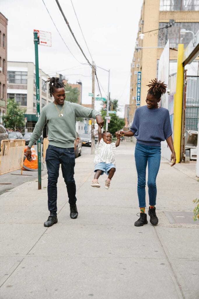 Joyful parents swinging their child during a walk in an urban area.